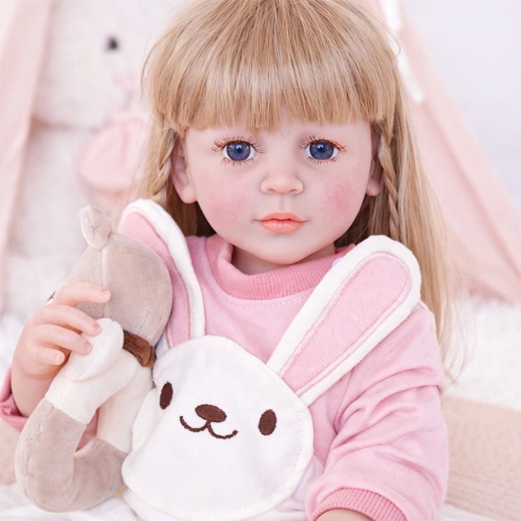 Chimidoll - muñeca renacida de niña pequeña, vestida con un conjunto de mono de conejito rosa.