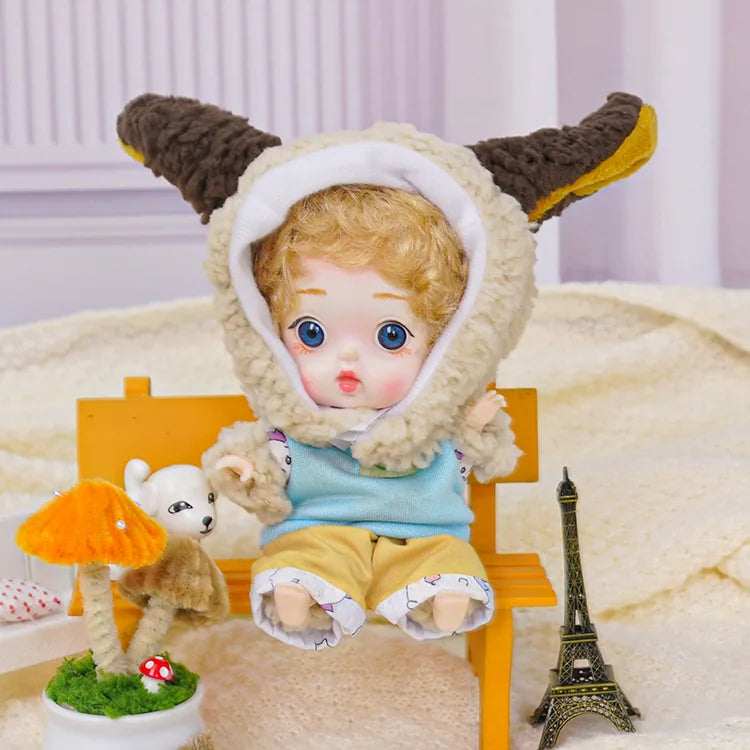 A golden-curled BJD wearing a lamb costume with adorable miniatures, including a Parisian Eiffel Tower replica.