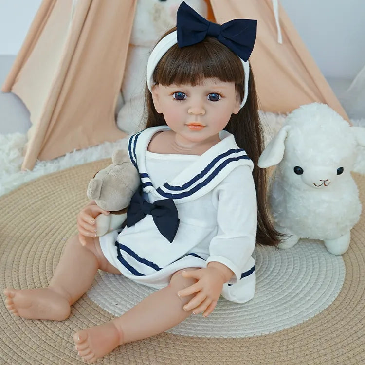 Reborn Toddler Doll sitting on the white chair, holding the bear plush, with a gentle expression.